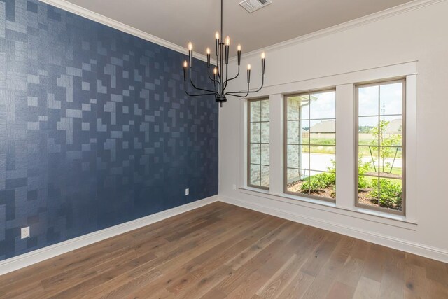 unfurnished dining area featuring wood finished floors, visible vents, an accent wall, baseboards, and a notable chandelier