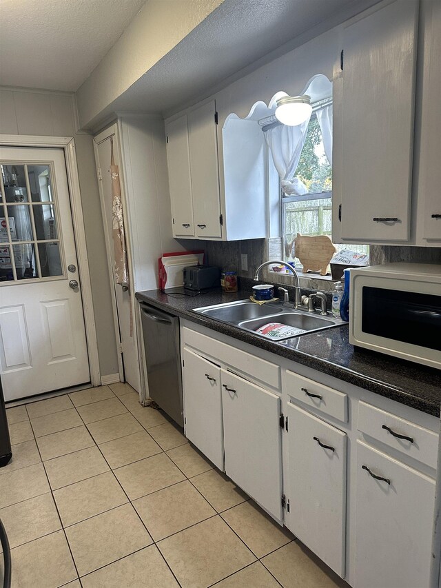 kitchen featuring stainless steel dishwasher, white cabinetry, sink, and light tile patterned floors