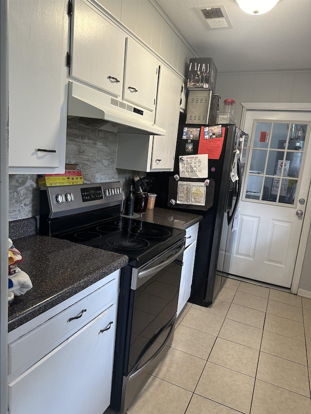 kitchen with dark stone counters, a textured ceiling, light tile patterned floors, white cabinetry, and stainless steel electric range