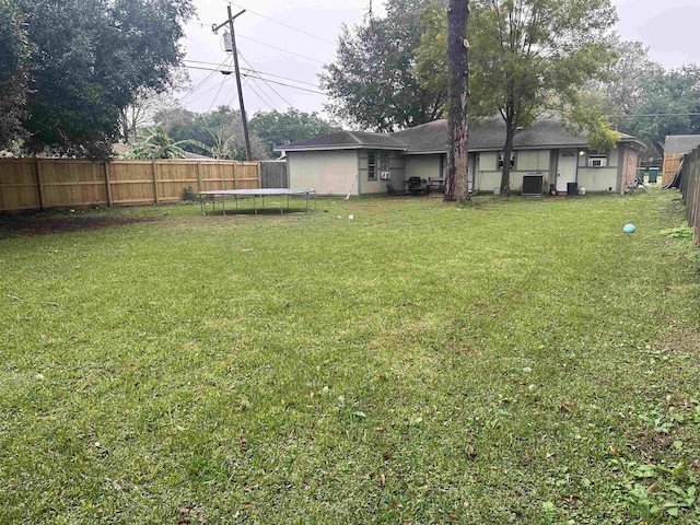 view of yard with central air condition unit and a trampoline