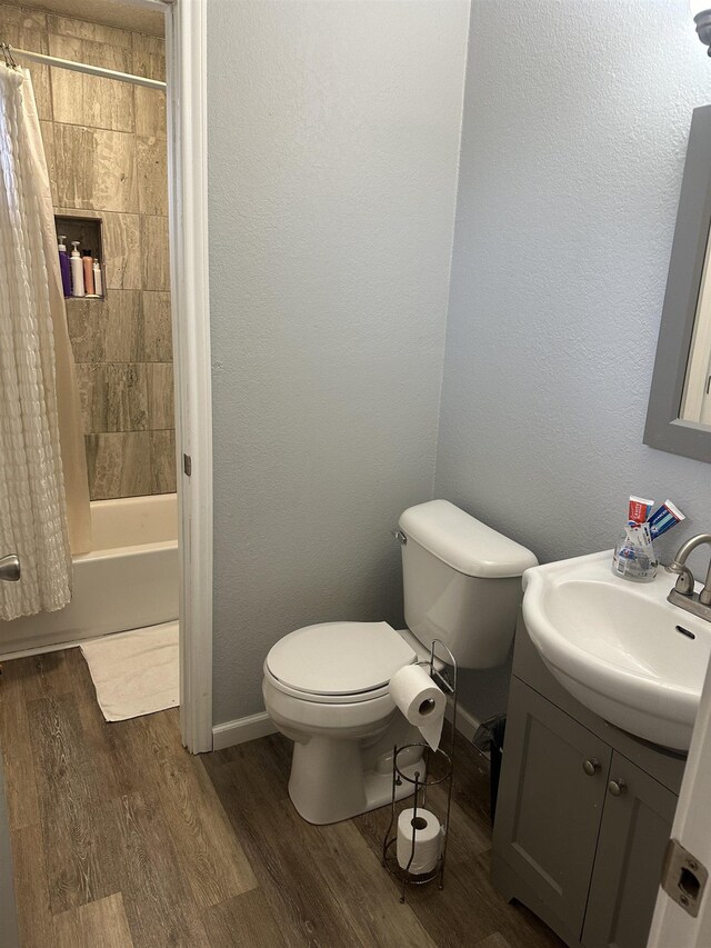 full bathroom featuring hardwood / wood-style floors, vanity, shower / bath combo, and toilet