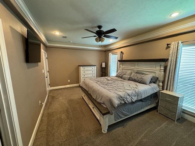 carpeted bedroom featuring a tray ceiling, ceiling fan, and ornamental molding