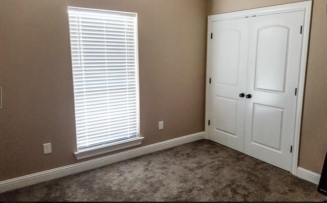 unfurnished bedroom with dark carpet and a closet