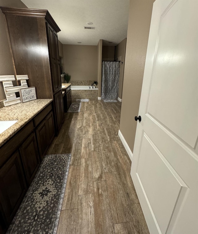 bathroom featuring plus walk in shower, vanity, and wood-type flooring