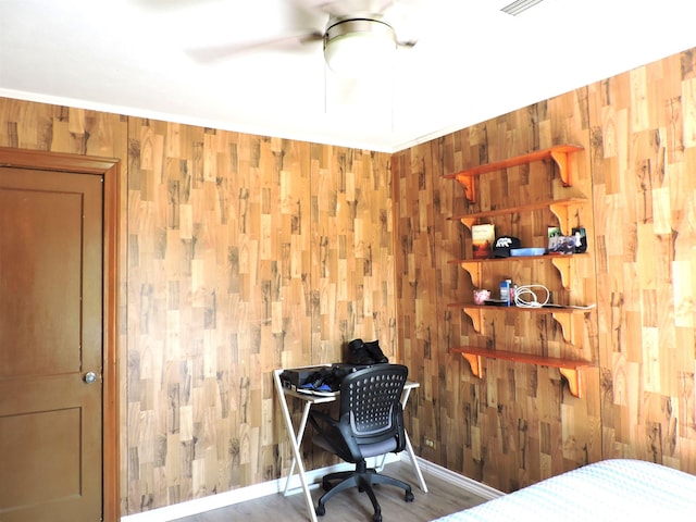 bedroom featuring wooden walls, baseboards, and wood finished floors