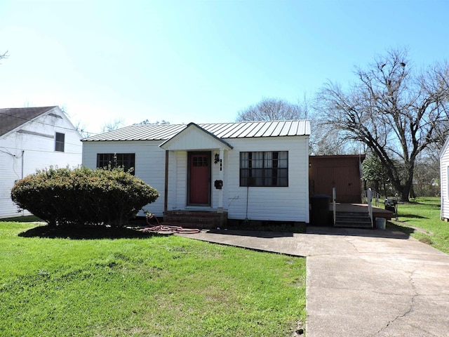 view of front of home featuring metal roof, driveway, and a front lawn