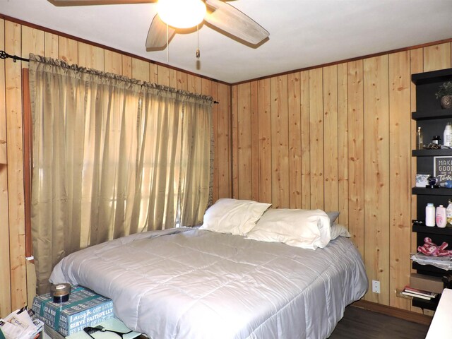 bedroom featuring wood walls, ceiling fan, ornamental molding, and wood finished floors