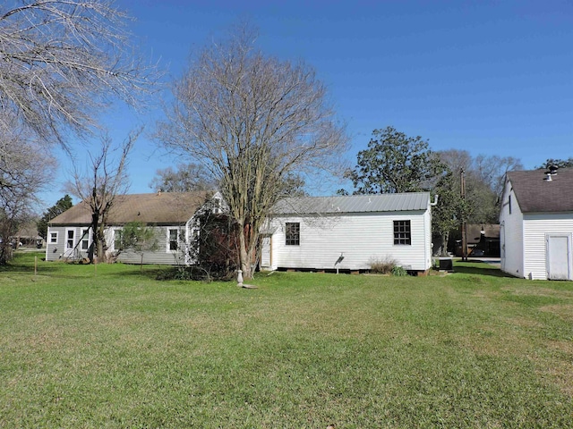 back of property featuring metal roof and a yard