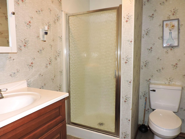 bathroom featuring toilet, wallpapered walls, a shower stall, and vanity