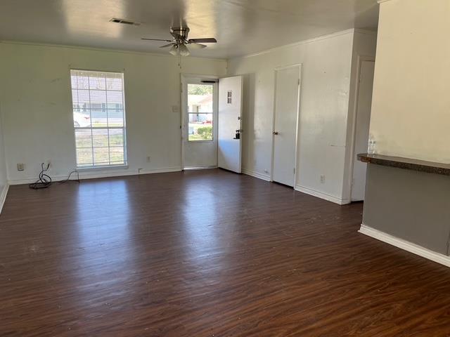 spare room with dark wood-style floors, ceiling fan, visible vents, and baseboards