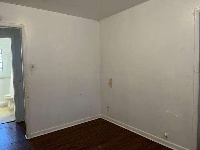 empty room featuring dark wood-style flooring and baseboards