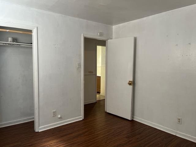 unfurnished bedroom with a closet, baseboards, and wood finished floors