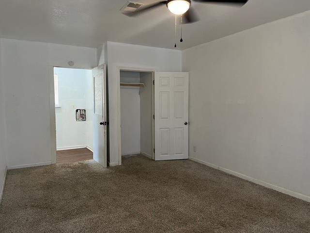 unfurnished bedroom with ceiling fan, carpet floors, visible vents, baseboards, and a closet