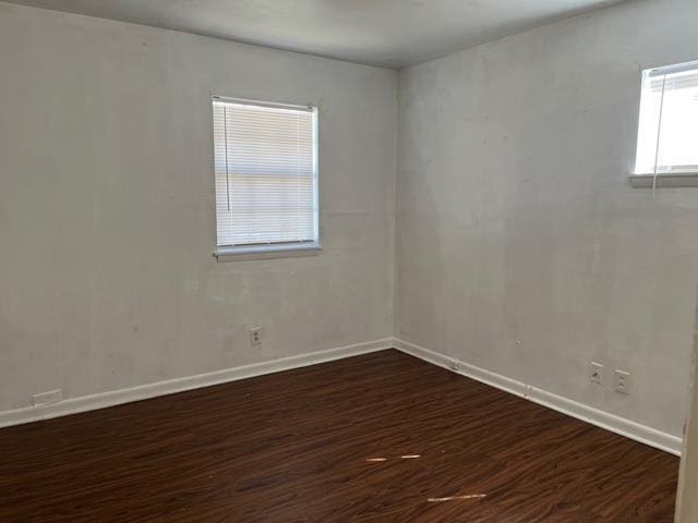 empty room with dark wood-type flooring and baseboards