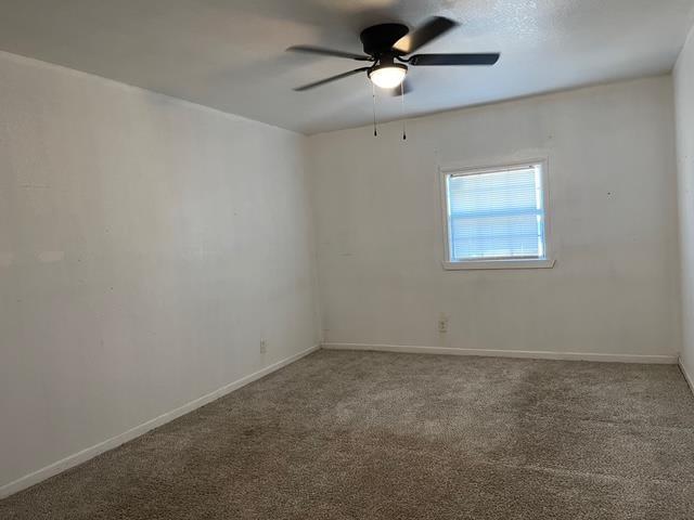 unfurnished room featuring carpet, baseboards, and a ceiling fan