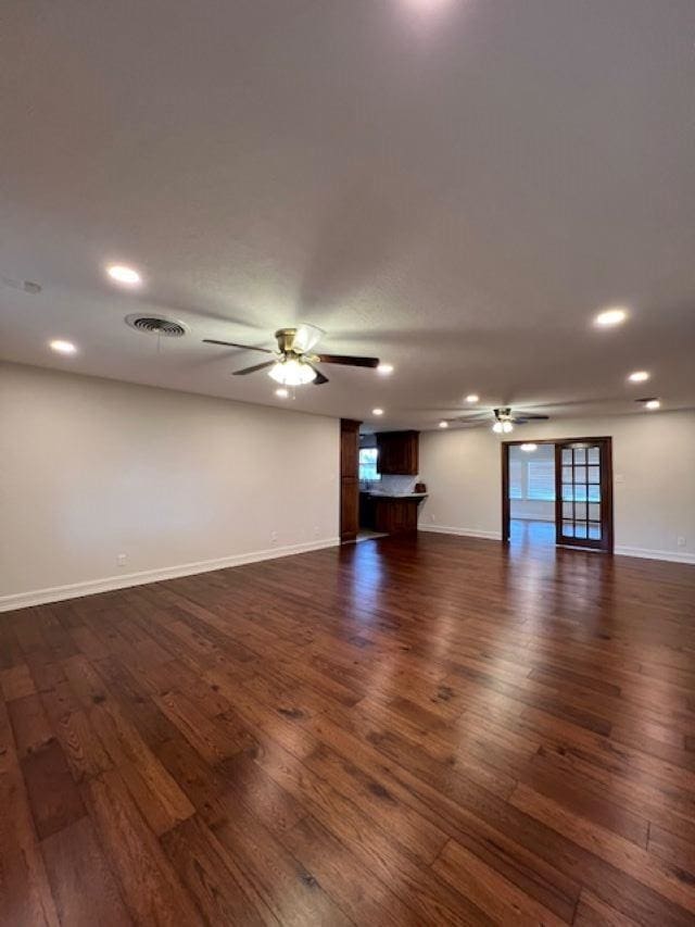 spare room with dark wood-style flooring, visible vents, ceiling fan, and baseboards