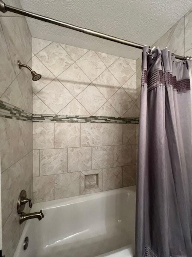 bathroom with shower / bathtub combination with curtain and a textured ceiling