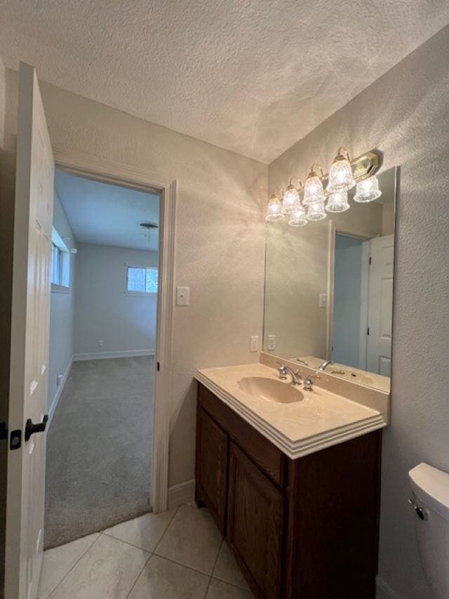 bathroom featuring a textured wall, toilet, a textured ceiling, vanity, and tile patterned floors