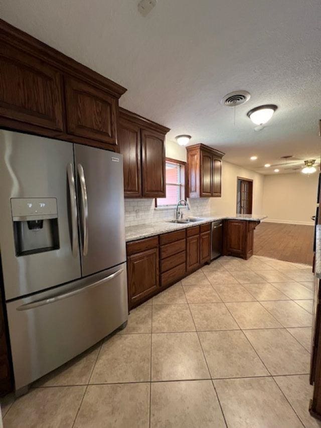 kitchen featuring appliances with stainless steel finishes, light tile patterned flooring, a sink, and backsplash