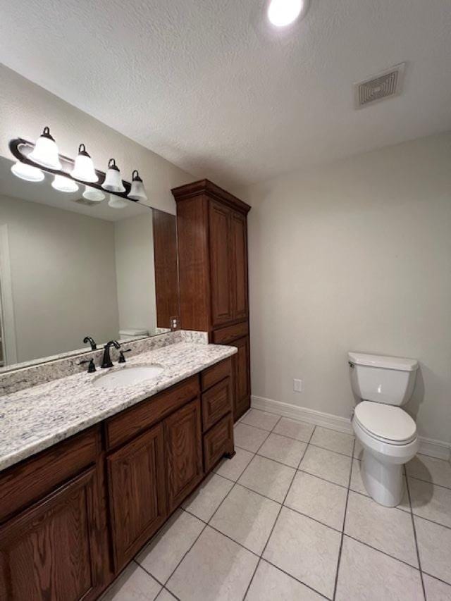 bathroom featuring baseboards, visible vents, toilet, tile patterned floors, and vanity