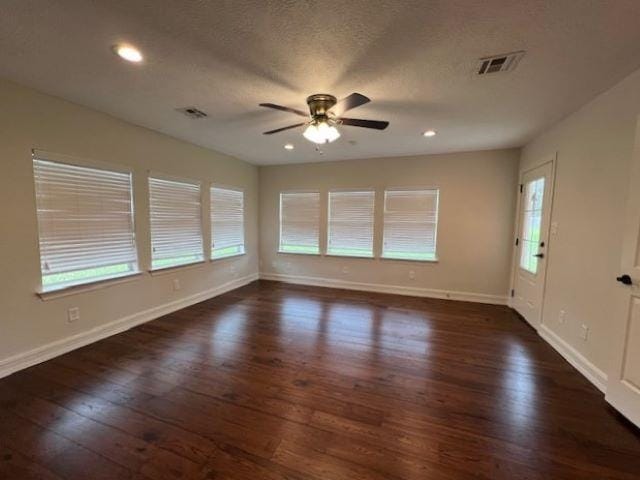 interior space featuring a textured ceiling, dark wood-type flooring, visible vents, and baseboards