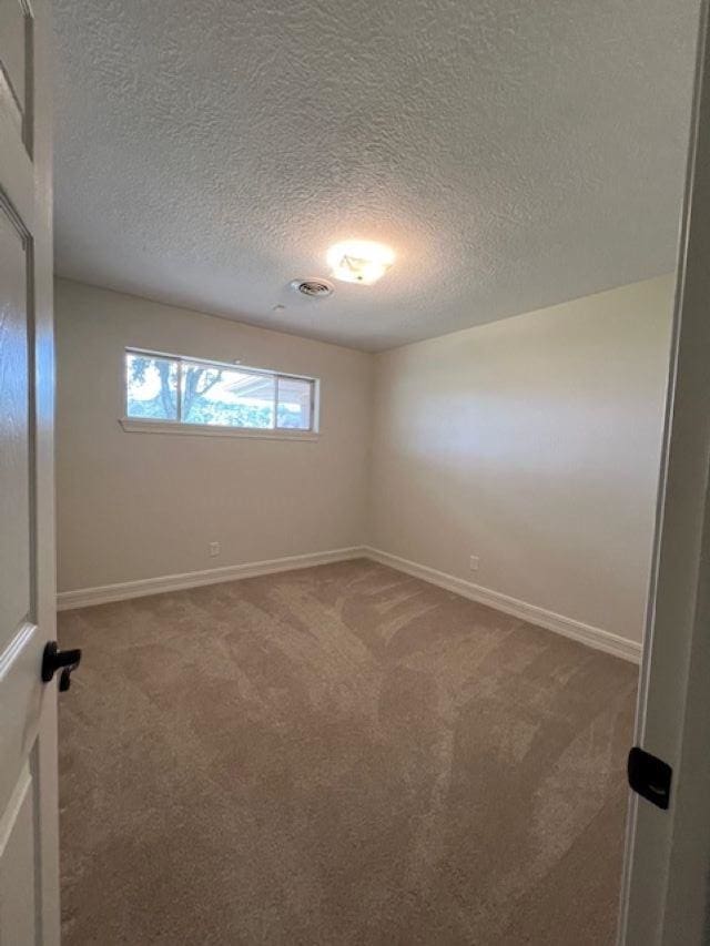 carpeted empty room featuring baseboards and a textured ceiling