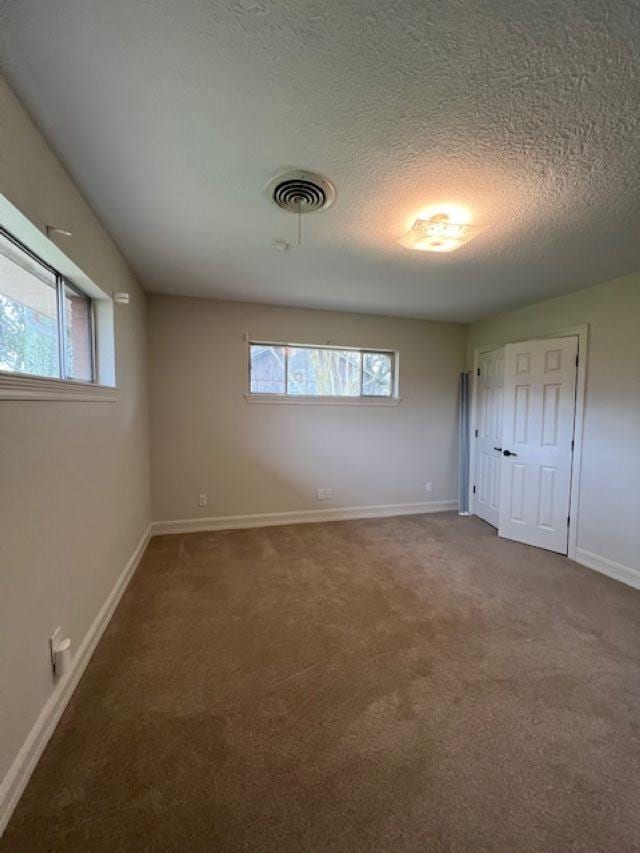 unfurnished bedroom featuring carpet floors, baseboards, visible vents, and a textured ceiling