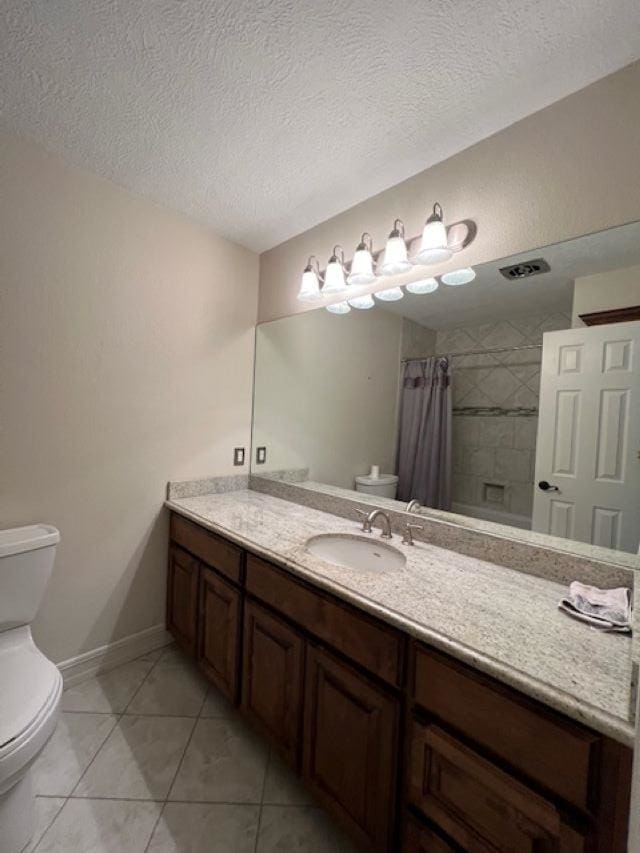 full bath with toilet, a textured ceiling, tiled shower, and vanity