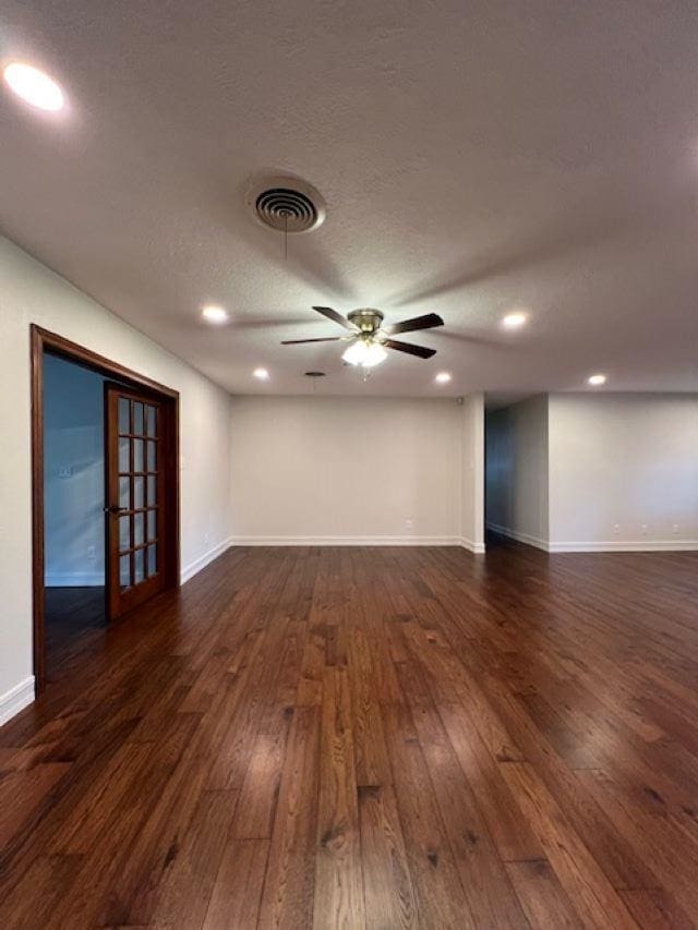 unfurnished room featuring visible vents, dark wood finished floors, a textured ceiling, and baseboards