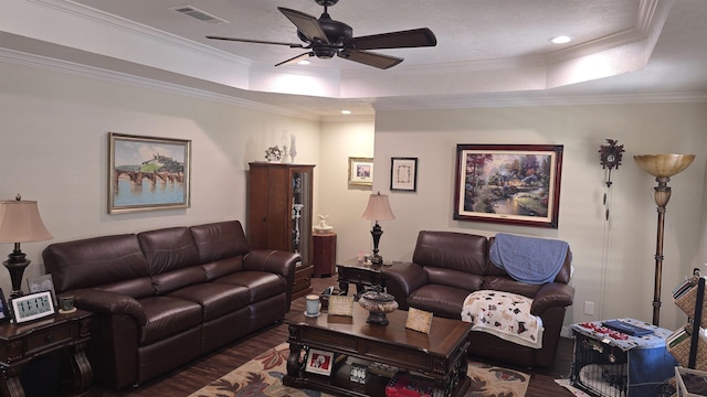 living room featuring visible vents, a raised ceiling, wood finished floors, and ornamental molding