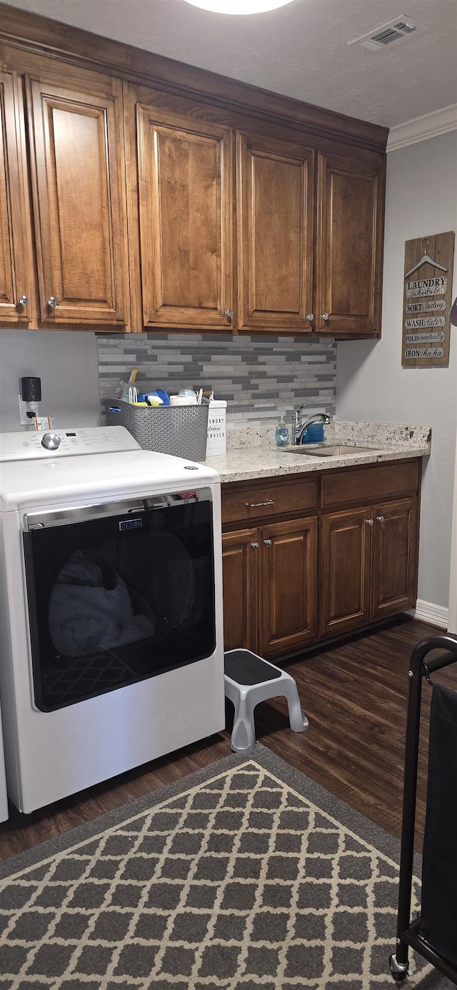 laundry area with dark wood-style floors, visible vents, cabinet space, ornamental molding, and a sink