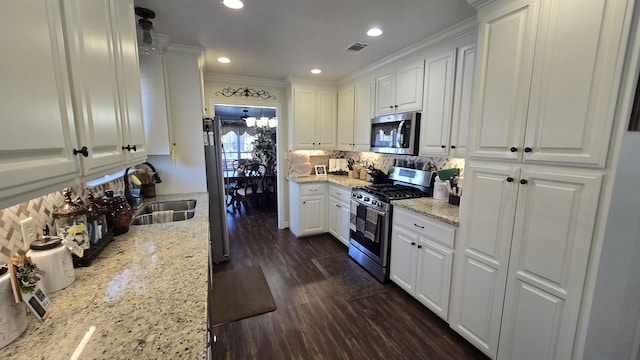 kitchen featuring dark wood-type flooring, a sink, backsplash, stainless steel appliances, and white cabinets