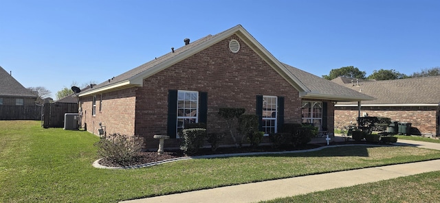 view of side of property with cooling unit, brick siding, a lawn, and fence