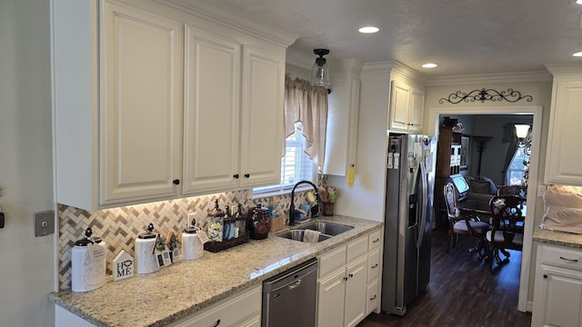 kitchen featuring dark wood-type flooring, a sink, backsplash, stainless steel appliances, and white cabinets