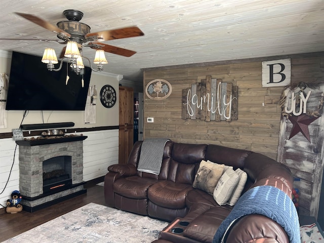 living room featuring a stone fireplace, wooden walls, crown molding, and dark wood-type flooring