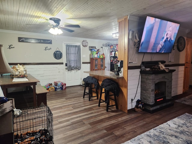 living room with a wood stove, hardwood / wood-style flooring, ceiling fan, and ornamental molding