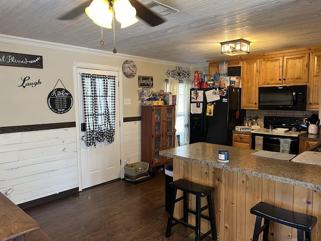 kitchen featuring black appliances, ceiling fan, ornamental molding, kitchen peninsula, and a breakfast bar area