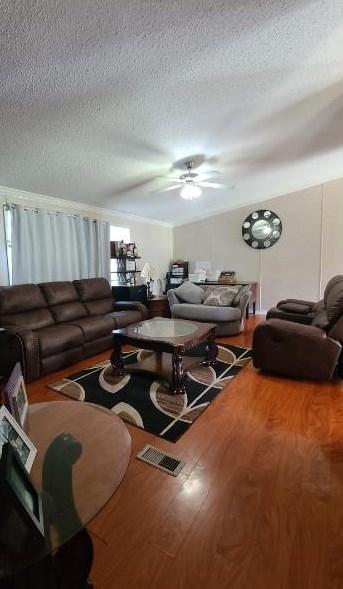 living room featuring hardwood / wood-style floors, ceiling fan, and a textured ceiling