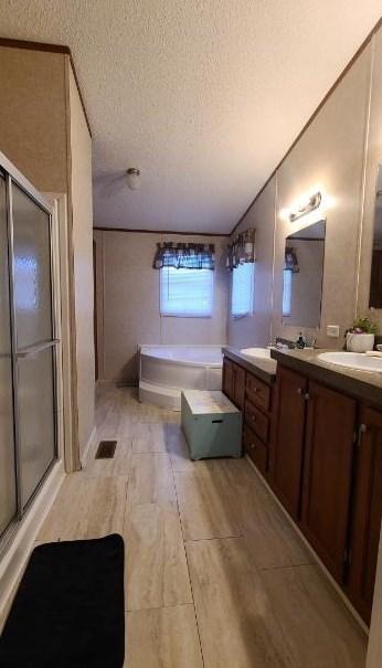 bathroom with vanity, independent shower and bath, a textured ceiling, and wood-type flooring