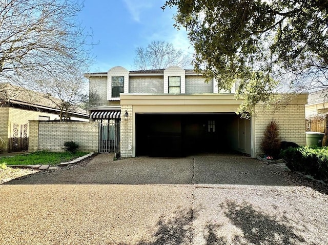 view of front facade with driveway, brick siding, and fence