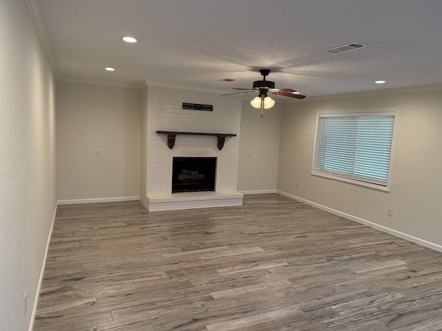 unfurnished living room with ceiling fan, crown molding, wood-type flooring, and a fireplace