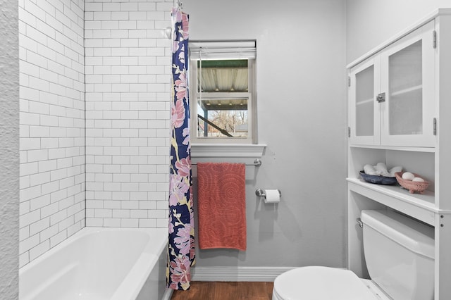 bathroom with hardwood / wood-style floors, shower / bathtub combination with curtain, and toilet