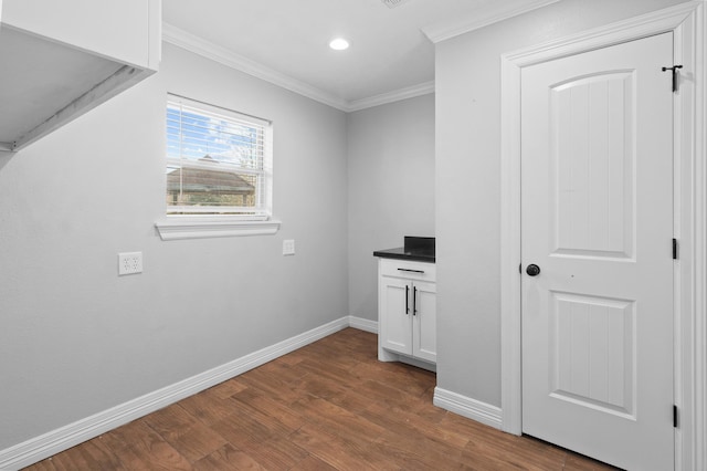 laundry area featuring crown molding and dark hardwood / wood-style floors