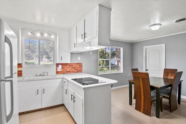 kitchen featuring black electric stovetop, white fridge, white cabinetry, and sink