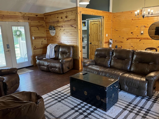 living room featuring dark wood-type flooring, wood walls, and a notable chandelier