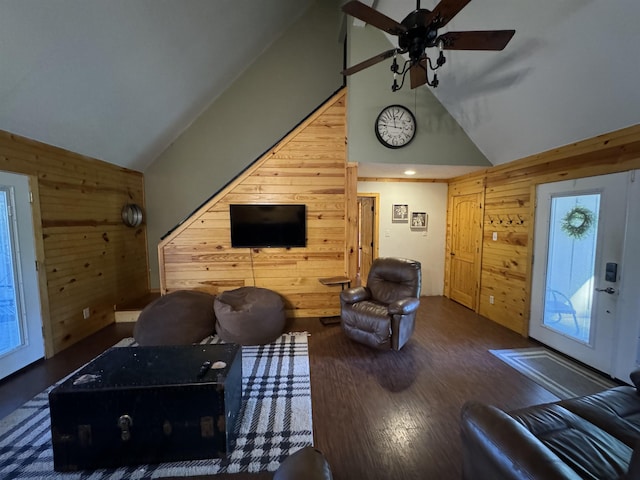 living room featuring ceiling fan, high vaulted ceiling, dark hardwood / wood-style flooring, and wood walls