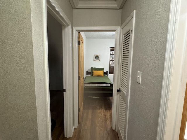 corridor featuring a textured ceiling, ornamental molding, and wood-type flooring