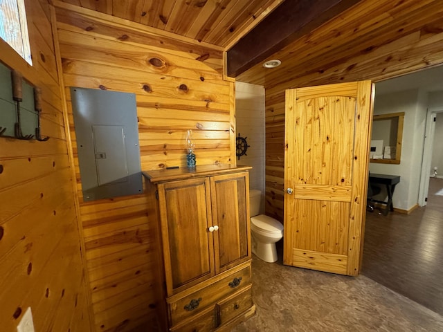 bathroom with electric panel, wood walls, wooden ceiling, and toilet