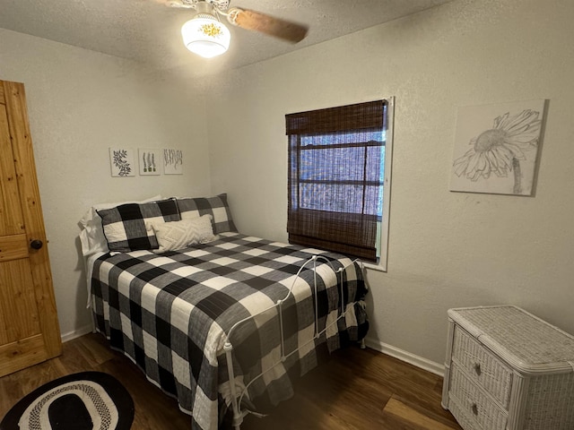 bedroom with ceiling fan, a textured ceiling, and dark hardwood / wood-style floors