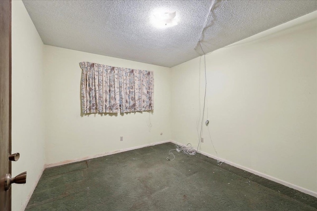 carpeted spare room featuring a textured ceiling and baseboards